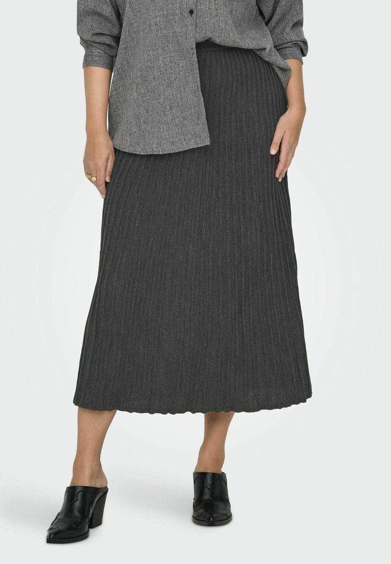 Gonna maxi grigia a costine con una texture morbida, caratterizzata da un orlo scallop. Abbinata a scarpe nere con tacco spesso e una camicia oversize con bottoni.