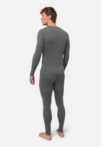 Graues eng anliegendes Thermo-Longsleeve und Leggings, gerippte Textur, nahtloses Design, mit langen Ärmeln und zulaufenden Beinen, barfuß getragen.