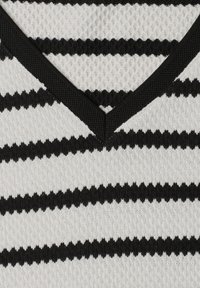 Gros plan d'un tissu tricoté à rayures noires et blanches avec un détail de bord en V.