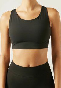 Schwarzer, nahtloser Sport-BH mit Rundhalsausschnitt und breiten Schulterträgern. Glatte Textur, mittellange Crop-Länge, entworfen für Sportbekleidung.