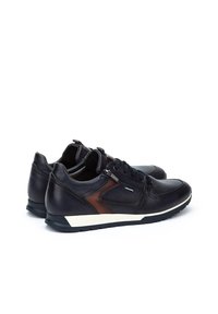 Scarpe in pelle nera con dettagli marroni, chiusura con lacci, punta tonda, suola bianca a contrasto e dettagli testurizzati nella parte superiore.