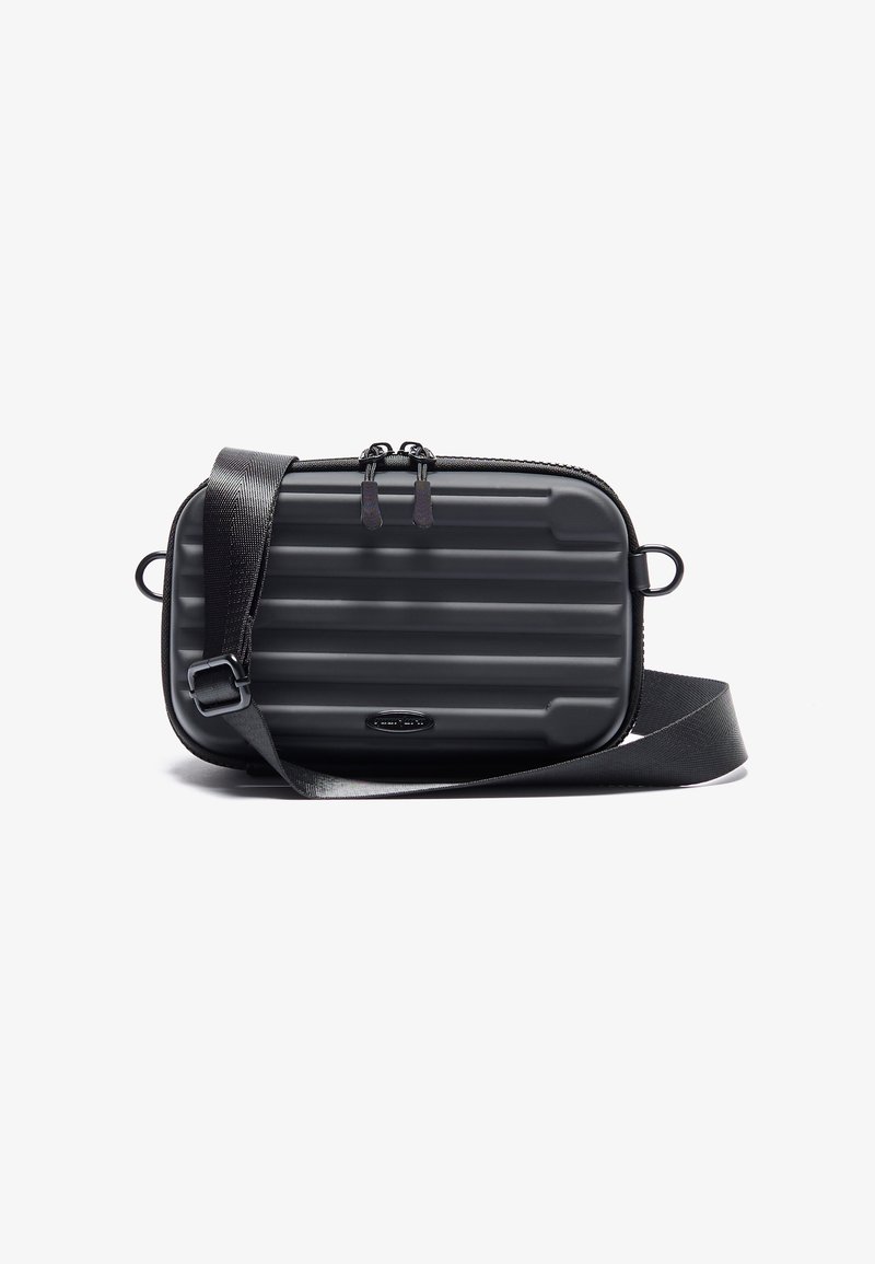 Kompakt sort taske med rillet overflade, justerbar rem, dobbelt lynlås og cirkulært logo accent. Fremstillet af holdbart materiale.