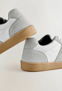 Pair of low-top sneakers with light gray suede, white leather panels, and gum rubber soles, shown from the back and side angles.