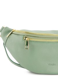 Groene leren heuptas met een gestructureerd oppervlak, gouden rits en een klein logo. Gecontourde vorm met een verstelbare band.
