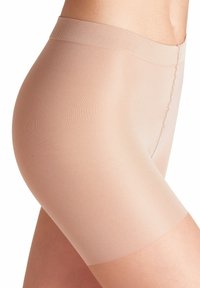 Pantaloni corti beige senza cuciture realizzati in materiale elasticizzato e leggero, caratterizzati da una texture liscia e una vita con un delicato dettaglio a filo.