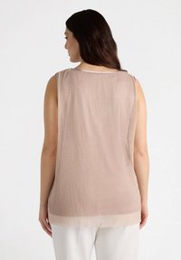 Ljusbrun ärmlös topp med vertikal ribbad struktur, rundad nacke och en rak fåll som lätt draperar sig över kroppen.