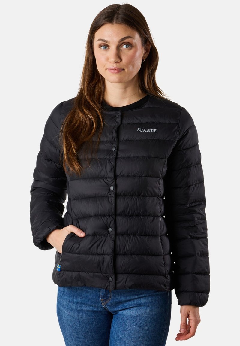 Veste doudoune noire avec un design matelassé, col rond, boutons sur le devant et poches latérales. Présente un petit logo sur la poitrine et une étiquette colorée.