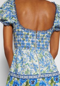 Květinové šaty v modrých a zelených odstínech, s nabíranými rukávy, smockovaným živůtkem a zipem na zádech. Texturovaná tkanina s výraznými vzory.