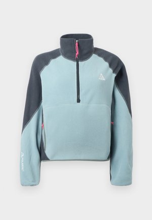 Fleece-pull med halv glidelås. Lys blå kropp, mørkegrå ermer, rosa glidelåsampule. Har sidelommer og 'Polartec'-logo på ermet.