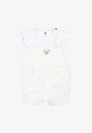 Shortalls blancs avec un motif floral bleu clair et jaune, présentant une appliqué d'ours, des boutons-pression aux épaules et des manches blanches froncées.