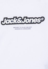 Fehér pamut póló, amelyen egy vastag fekete "Jack&Jones" logó látható, vastag körvonalban. További szöveg kisebb betűméretben alul.