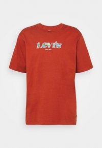 T-shirt en coton rouge à manches courtes, arborant un logo "Levi's" multicolore et le texte "Since 1873" sur le devant. Col rond.