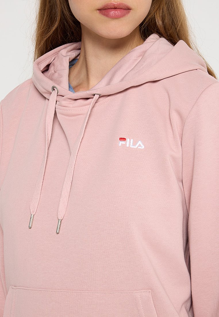 Roze hoodie met een trekkoordcapuchon, geribde manchetten en een voork pocket. Bevat een geborduurd wit "FILA" logo op de borst. Zachte stoftextuur.
