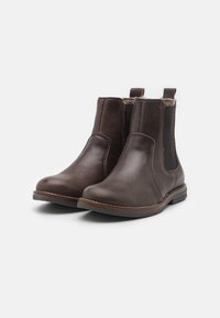 Botas de tobillo de cuero marrón con paneles laterales elásticos, punteras redondeadas y costuras visibles. Suelas de goma texturizada para agarre y durabilidad.