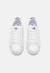 Baskets de sport blanches avec une tige en cuir lisse, bout rond et semelle en caoutchouc plate. Présentent des lacets blancs et un subtile accent noir au niveau du talon.