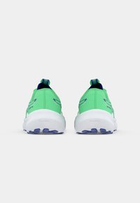 Zapatillas deportivas verdes con un upper texturizado, que cuentan con una tira para facilitar el calzado, una entresuela blanca ligera y acentos morados en la suela.