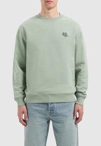 Muntgroene sweatshirt gemaakt van een zacht materiaal, met een ronde hals, geribbelde manchetten en onderrand, en een klein grafisch logo op de borst.