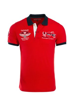 Crvena polo majica s mornarsko plavim ovratnikom i rubovima rukava, s bijelim i crvenim logotipima i tekstom trkaćeg tima na prednjoj strani i rukavima.