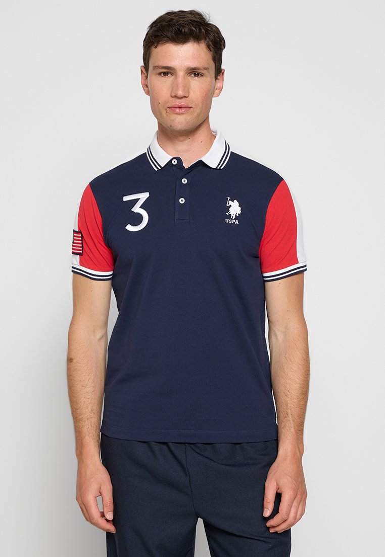 Polo shirt marine avec des manches rouges, un col blanc et des rayures horizontales. Presentant un logo brodé et un grand numéro "3" sur la poitrine.