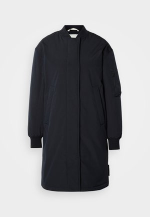 Tumesinine pikk mantel, mis on valmistatud siledast kangast, kõrge krae, küljetaskute ja lukuga varrukataskuga ning elastsete mansettidega.