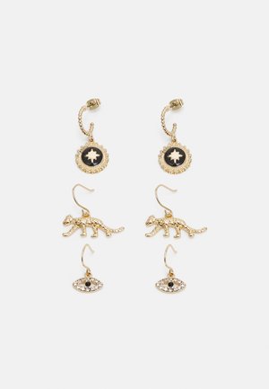 Brincos de ouro com um encanto circular apresentando um fundo preto e um design de folha, uma forma de leopardo e um encanto de olho com detalhes pretos.