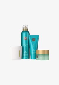 Sett med fem hudpleieprodukter: blågrønne flasker og tuber med gullaksenter, hvit teksturert krukke, etiketter med svart tekst og lys grønn krem.