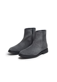 Bottes de cheville en suède gris au design minimaliste, avec une semelle en caoutchouc plate et une fermeture éclair sur le côté pour un enfilage facile. Texture lisse, forme classique.