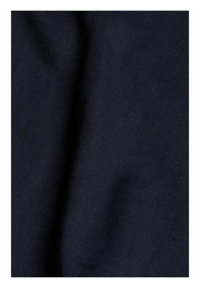 Dunkelnavyblauer Stoff mit einer diagonalen Köpergewebestruktur und sanften Falten, die Schatten und Highlights erzeugen.