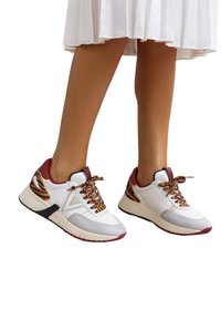 Sneaker bianche con dettagli rossi, dettagli grigi testurizzati e stampa animalier, con suola imbottita e suola esterna in gomma nera a contrasto.