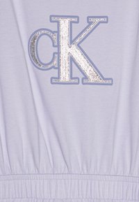 Jasnofioletowy bawełniany ubiór z dużym, błyszczącym srebrnym logo "CK" z obramowaniem oraz elastycznym, marszczonym pasem u dołu.