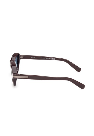 Hnědé plastové sluneční brýle s tmavými skly, které mají elegantní design a stříbrné detaily na straně. Mají hladký povrch a zúžené stranice.