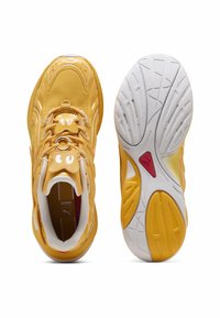 Baskets jaunes avec des superpositions en maille et en synthétique, design à lacets, col rembourré et semelle extérieure blanche contrastante avec des motifs texturés.