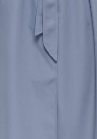 Light blue fabric with a smooth texture, featuring a tied detail at the waist and a straight cut, showcasing clean lines and minimal stitching.