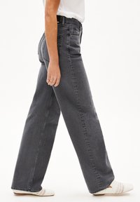 Högmidjade, vida jeans i mörkgrå denim, med en klassisk femficksdesign och subtila sömmar. Accentuerade med en vävd sko.