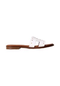 Sandale plate marron avec une large sangle en cuir blanc comportant des découpes et de petits clous dorés, présentée sur un fond blanc uni.
