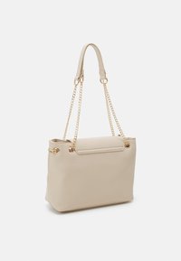 Beiger synthetischer Shopper mit goldfarbenen Kettenriemen, flacher Form, glatter Textur und dekorativen Metallakzenten.