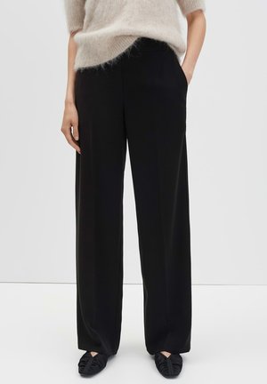 Black wide-leg trousers with a smooth texture, featuring side pockets and a tailored fit, paired with flat black fabric shoes.