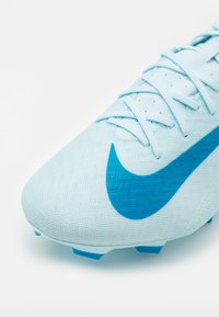 Botín de fútbol azul claro con parte superior texturizada, que presenta un gran swoosh azul de Nike y tacos de suela azul contrastantes.