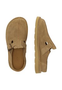 Beige Wildlederschlupfschuhe mit einem Ausschnitt-Design, verstellbarem Riemen mit Schnalle und Gummisohle, die ein strukturiertes Profil aufweist.