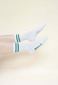 Weiße Socken mit grünen Streifen oben und dem Wort "Dop" in Grün bedruckt. Gerippte Textur. Socken sichtbar von der Mitte der Wade bis zu den Zehen.
