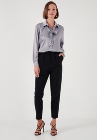 Silky gray blouse with a bow tie collar, paired with black trousers and strappy black heeled sandals, featuring a tailored fit.