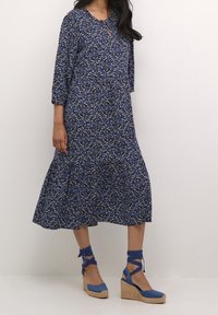 Květinový potisk, modré šaty s tříčtvrtečními rukávy, víceúrovňový lem, měkká látka. V kombinaci s modrými espadrilkami na wedges, zavazováním kolem kotníků.