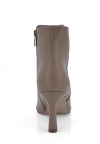 Bota de cuero marrón hasta el tobillo con tacón alto, cierre de cremallera lateral, textura suave y diseño ajustado. Presenta una punta afilada y una silueta elegante.