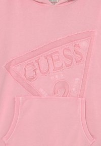 Jasnoróżowa bluza z kapturem wykonana z miękkiego materiału, z teksturowanym logo, postrzępionymi brzegami i przednią kieszenią typu kangur.