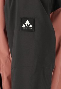 Musta ja vaaleanpunainen takki, jossa on teksturoitu kangas, logopatch, jossa on vuoristoteema, ja sivureikä paremman liikkuvuuden lisäämiseksi.