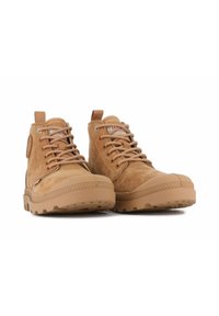 Stivali in suede beige con punta tonda, design con lacci, suole in gomma e un accento cucito lungo il bordo della suola. L'etichetta sul lato mostra il marchio.