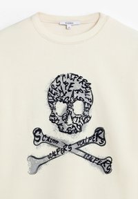 Sudadera beige con un diseño de calavera en negro y gris, con huesos cruzados y texto repetido, cuello redondo y puños acanalados.