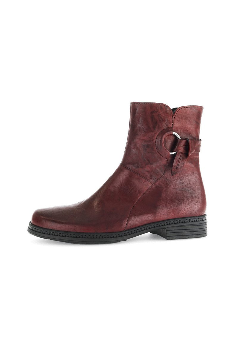Bottine cheville en cuir rouge avec une texture lisse, bout arrondi et un petit accent métallique circulaire sur le côté. Talon bas et semelle noirs.