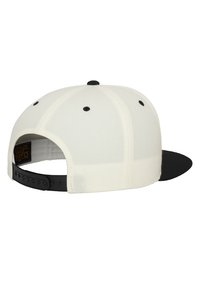 Cappello bianco con visiera nera, caratterizzato da un design strutturato e una fibbia nera in plastica regolabile sul retro. Visibili due fori di ventilazione neri.