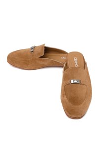 Paire de mocassins marron en daim à enfiler avec détail de boucle métallique et logo imprimé sur la semelle intérieure, présentée sur fond blanc.